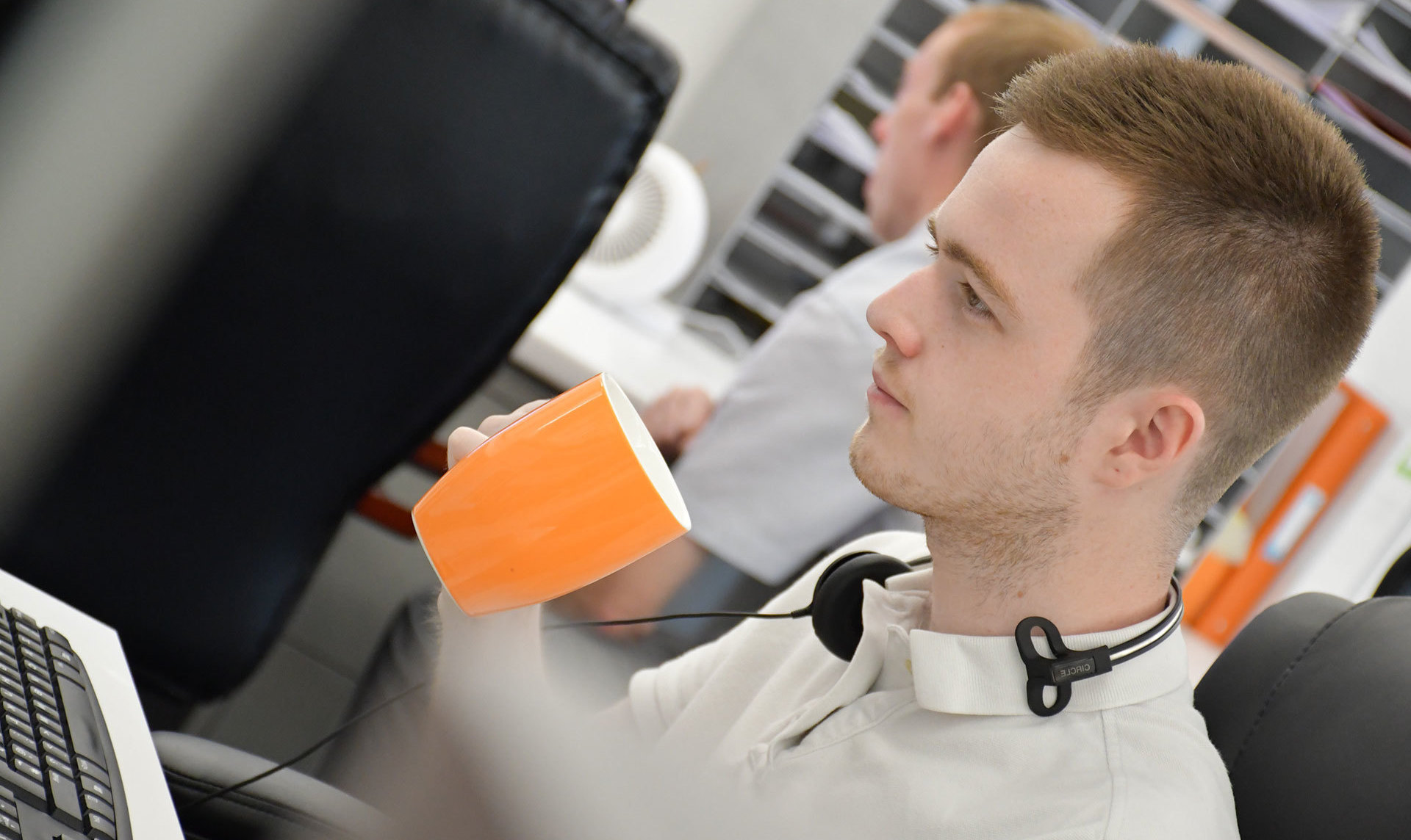 A website support worker looking at a laptop while drinking from a cup